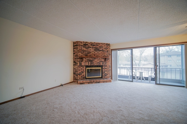 unfurnished living room with carpet flooring, a textured ceiling, and a brick fireplace