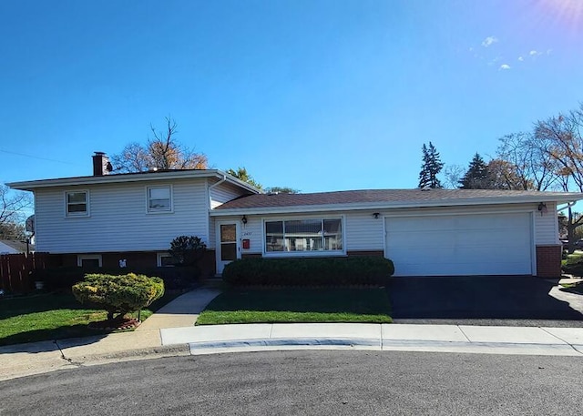 split level home with a garage and a front lawn