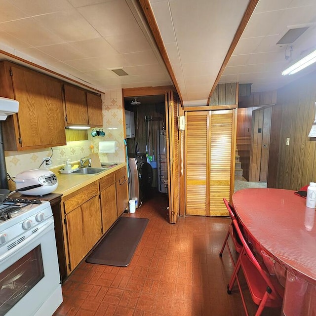 kitchen featuring wood walls, sink, ventilation hood, white gas stove, and gas water heater