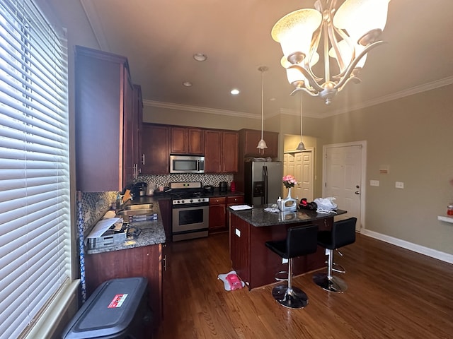 kitchen with stainless steel appliances, dark hardwood / wood-style flooring, a kitchen island, pendant lighting, and dark stone countertops