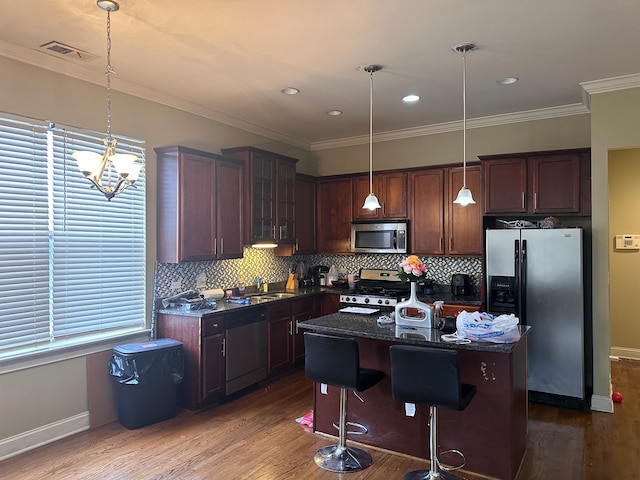 kitchen with dark hardwood / wood-style flooring, a center island, hanging light fixtures, a breakfast bar, and appliances with stainless steel finishes