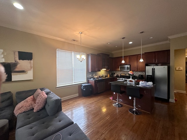 kitchen with stainless steel appliances, decorative light fixtures, crown molding, a center island, and dark wood-type flooring