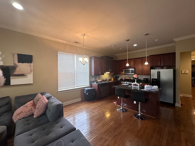 kitchen featuring stainless steel appliances, decorative light fixtures, crown molding, a kitchen island, and dark wood-type flooring