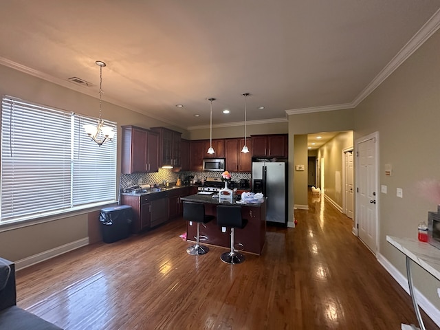 kitchen with appliances with stainless steel finishes, hanging light fixtures, a kitchen island, and a breakfast bar