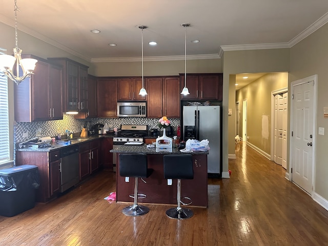 kitchen with stainless steel appliances, a kitchen island, dark hardwood / wood-style flooring, hanging light fixtures, and a breakfast bar area