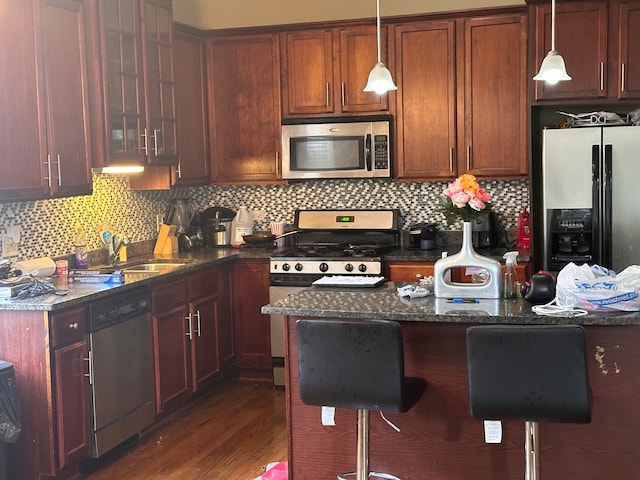 kitchen with stainless steel appliances, tasteful backsplash, dark stone countertops, and a breakfast bar