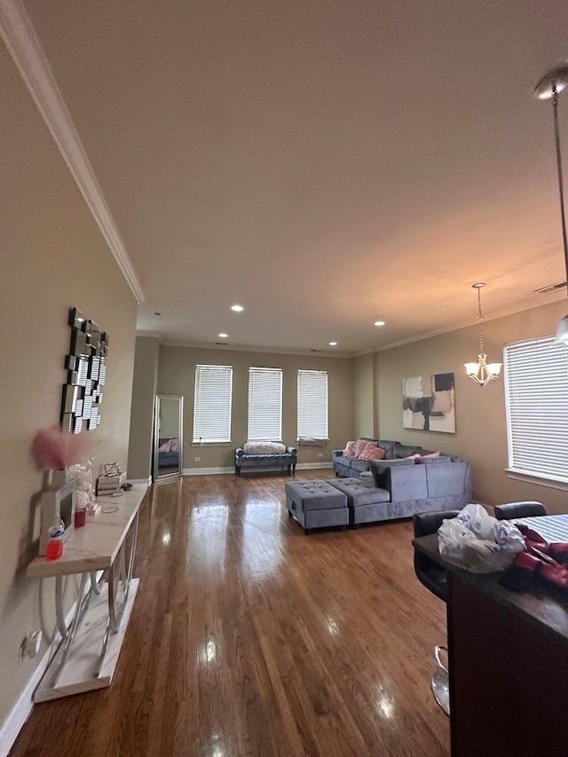 living room with ornamental molding, wood-type flooring, and an inviting chandelier