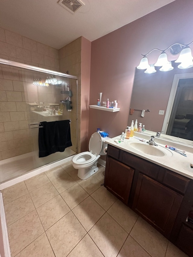 bathroom with a shower with door, vanity, toilet, and tile patterned floors