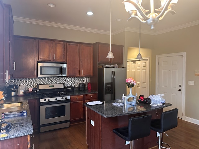 kitchen featuring sink, appliances with stainless steel finishes, dark hardwood / wood-style floors, a kitchen island, and pendant lighting