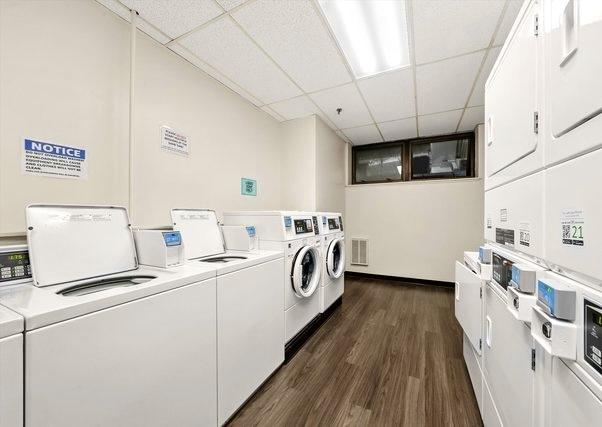 common laundry area featuring washer and clothes dryer, visible vents, stacked washer / drying machine, and dark wood-type flooring