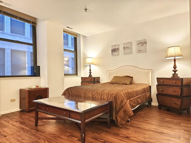 bedroom with visible vents, baseboards, and wood finished floors