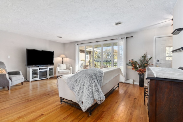 bedroom with a textured ceiling, access to outside, wood-type flooring, and a baseboard radiator