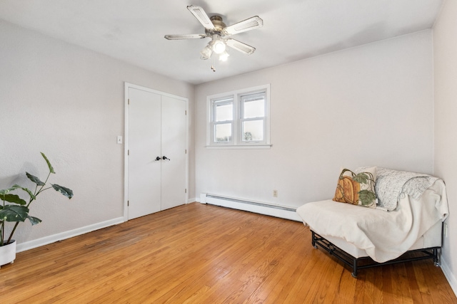 sitting room featuring ceiling fan, baseboard heating, and light wood-type flooring