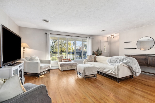 bedroom featuring light wood-type flooring, a textured ceiling, and baseboard heating