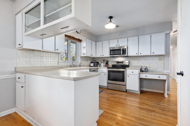 kitchen featuring stainless steel appliances, white cabinetry, sink, light hardwood / wood-style flooring, and decorative backsplash