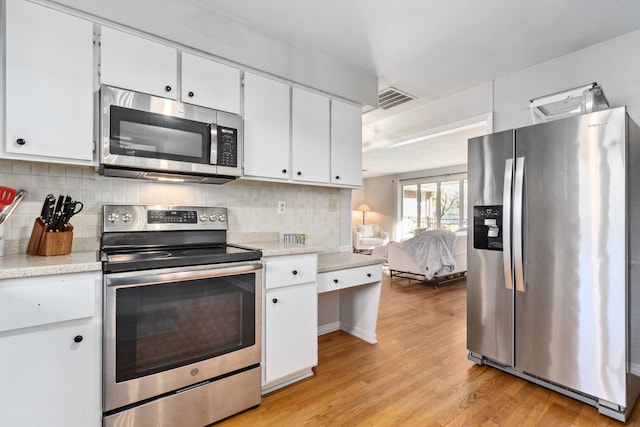 kitchen with white cabinetry, appliances with stainless steel finishes, backsplash, and light hardwood / wood-style flooring