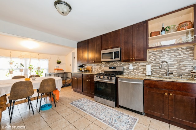 kitchen featuring tasteful backsplash, light stone counters, stainless steel appliances, light tile patterned floors, and sink