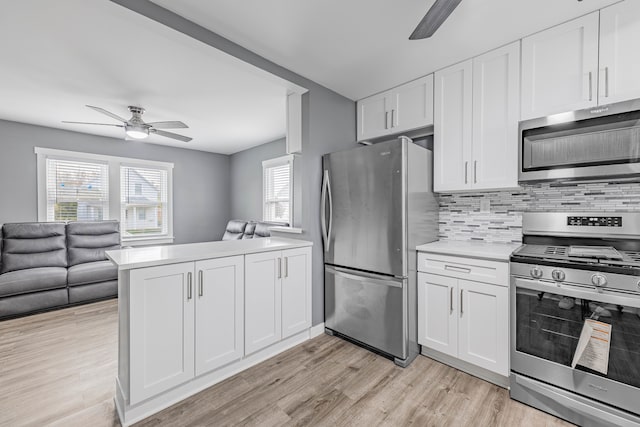 kitchen with white cabinets, kitchen peninsula, appliances with stainless steel finishes, and light hardwood / wood-style flooring