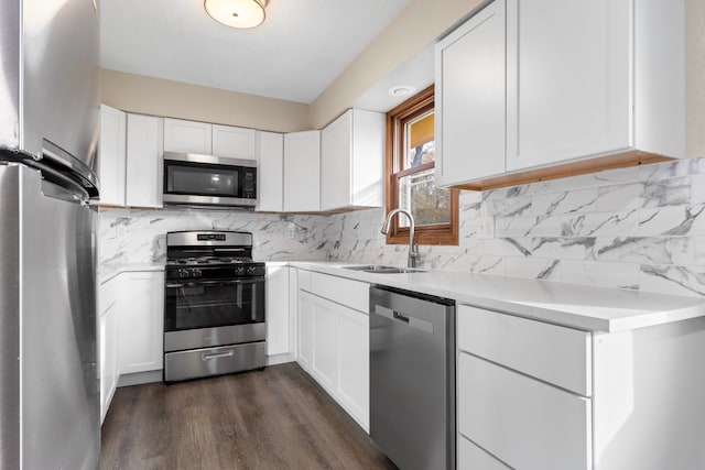 kitchen with sink, dark hardwood / wood-style floors, backsplash, white cabinetry, and appliances with stainless steel finishes