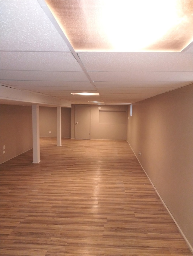 basement with hardwood / wood-style flooring and a drop ceiling