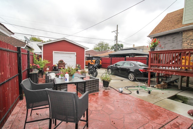 view of patio / terrace with an outbuilding, a garage, a deck, and an outdoor living space