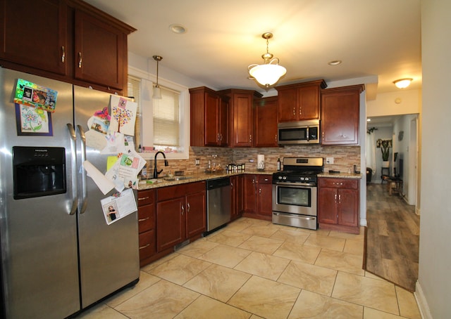 kitchen featuring light stone countertops, hanging light fixtures, decorative backsplash, and stainless steel appliances