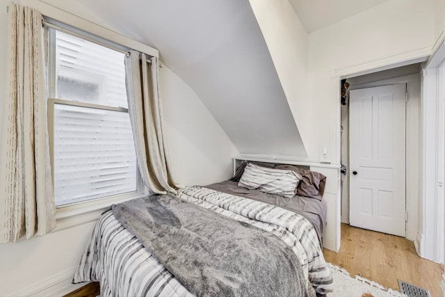 bedroom featuring light hardwood / wood-style flooring and lofted ceiling