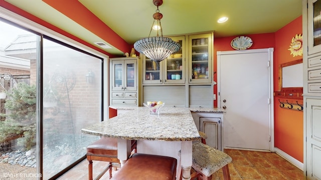 kitchen featuring hanging light fixtures, light stone countertops, a kitchen breakfast bar, and an inviting chandelier