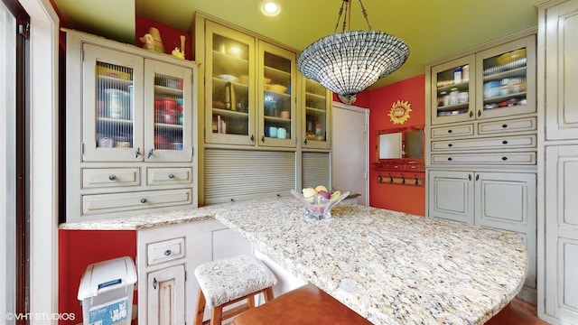 704 Lorraine Cir, Highland Park, IL 60035 - kitchen with a chandelier, glass insert cabinets, light stone counters, a breakfast bar, and recessed lighting
