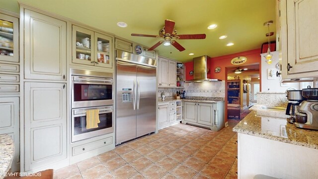 704 Lorraine Cir, Highland Park, IL 60035 - kitchen with stainless steel appliances, wall chimney exhaust hood, a ceiling fan, decorative backsplash, and light tile patterned flooring
