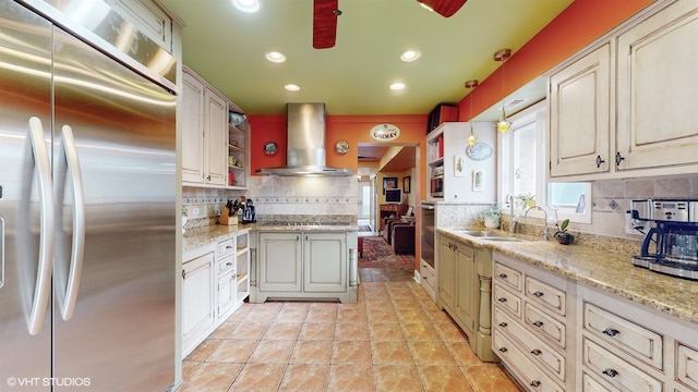 kitchen featuring stainless steel appliances, sink, light stone counters, wall chimney exhaust hood, and backsplash