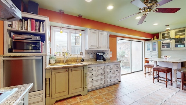 kitchen with stainless steel appliances, decorative backsplash, sink, ceiling fan, and decorative light fixtures