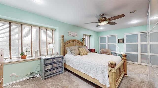 bedroom with multiple windows, light colored carpet, and ceiling fan