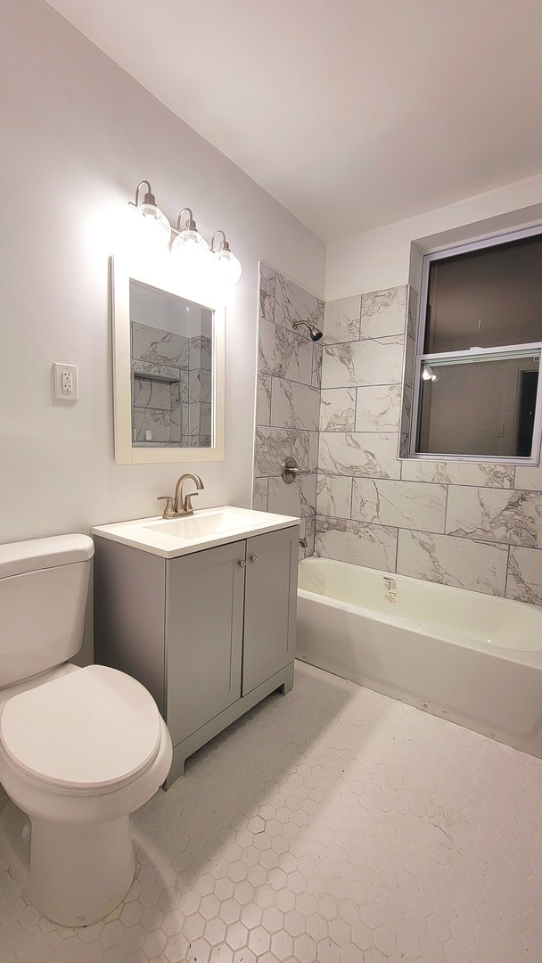 full bathroom with vanity, tile patterned flooring, tiled shower / bath, and toilet