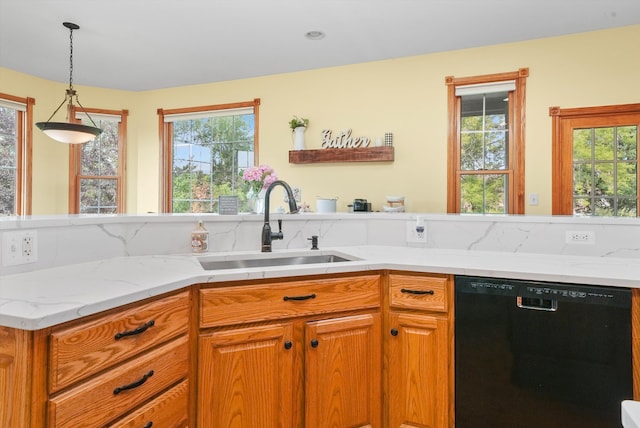 kitchen featuring light stone countertops, sink, decorative light fixtures, and black dishwasher