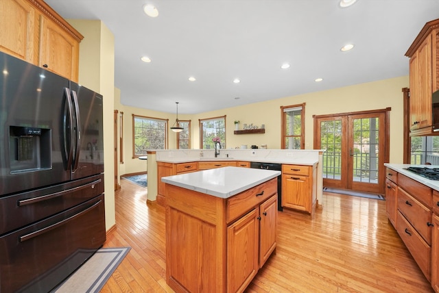 kitchen with pendant lighting, black appliances, a healthy amount of sunlight, and a center island