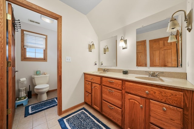 bathroom with toilet, vanity, vaulted ceiling, and tile patterned flooring