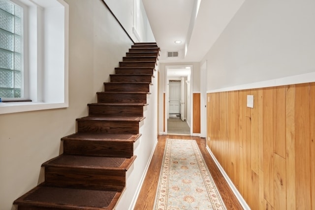 stairway featuring wood walls and hardwood / wood-style flooring