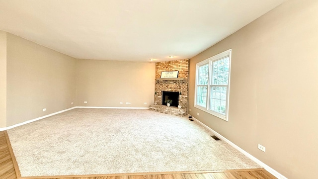 unfurnished living room featuring hardwood / wood-style floors and a brick fireplace