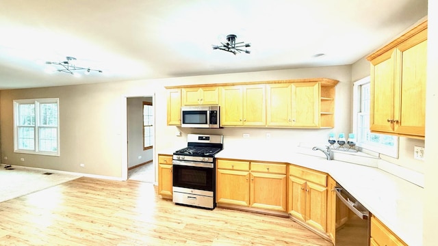 kitchen with a wealth of natural light, light brown cabinetry, light wood-type flooring, and appliances with stainless steel finishes