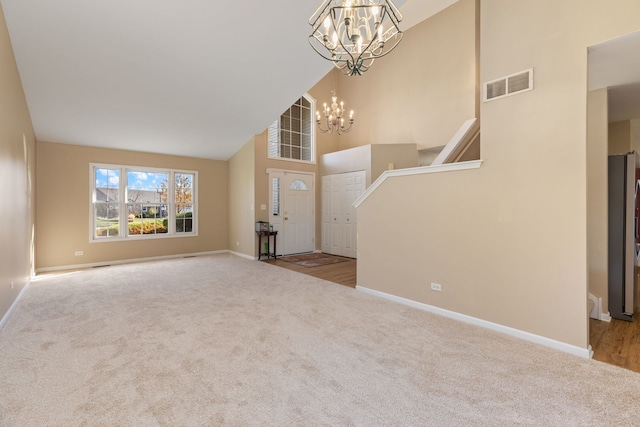 unfurnished living room with carpet flooring, a notable chandelier, and high vaulted ceiling