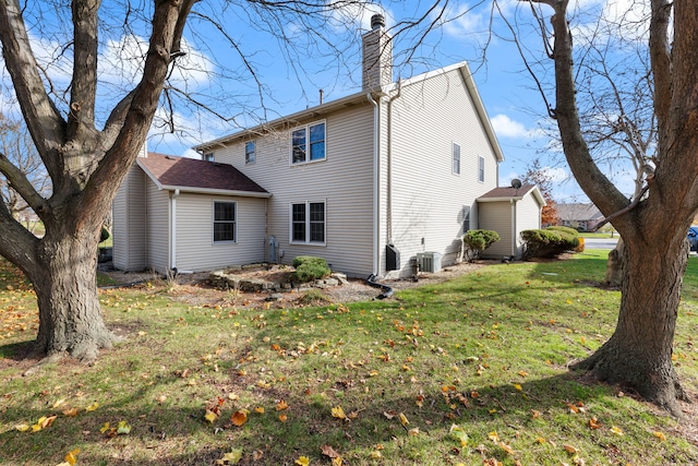 rear view of property with central air condition unit and a lawn