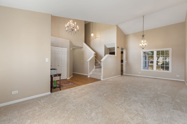 unfurnished living room featuring light carpet, high vaulted ceiling, and a chandelier