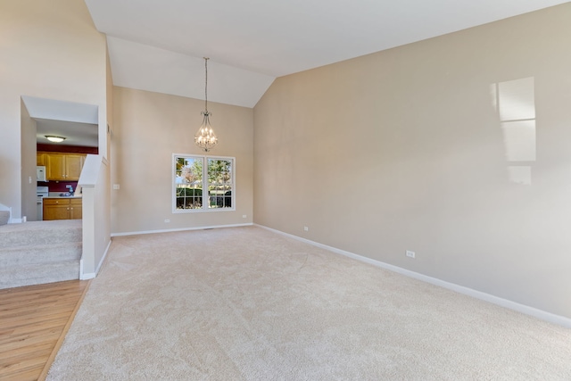 spare room featuring light colored carpet, lofted ceiling, and a chandelier