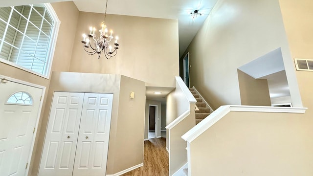 foyer featuring ceiling fan with notable chandelier, light wood-type flooring, and a towering ceiling