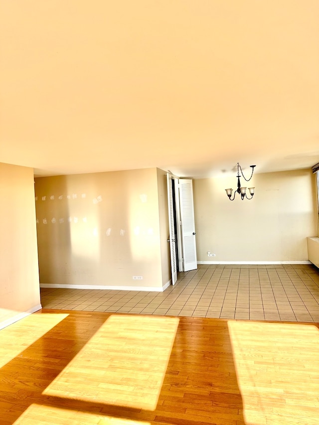 spare room with light hardwood / wood-style floors and an inviting chandelier