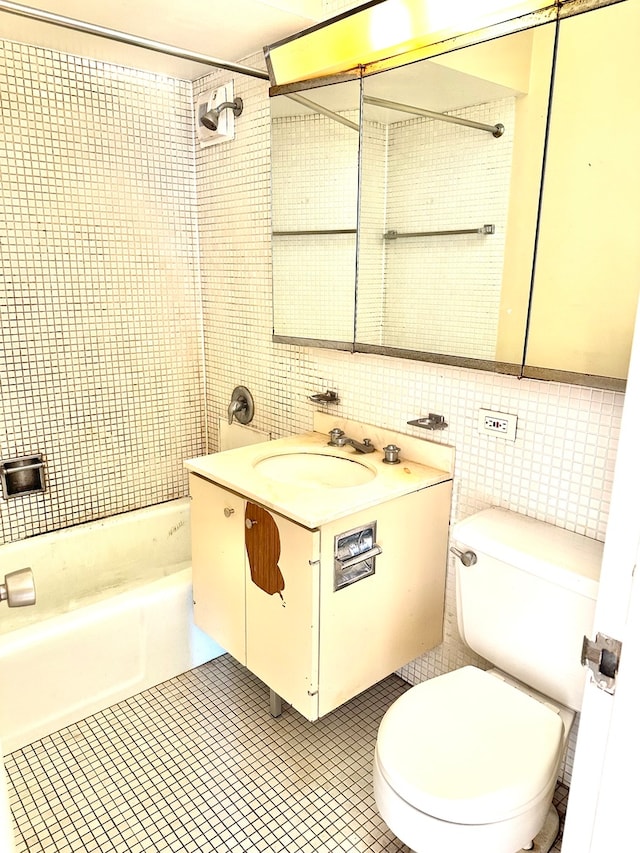 full bathroom featuring tile patterned flooring, tiled shower / bath, vanity, toilet, and tile walls