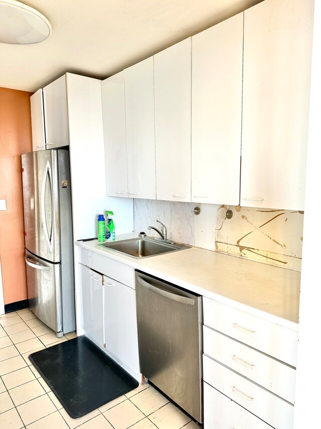 kitchen with white cabinetry, stainless steel appliances, sink, and light tile patterned floors