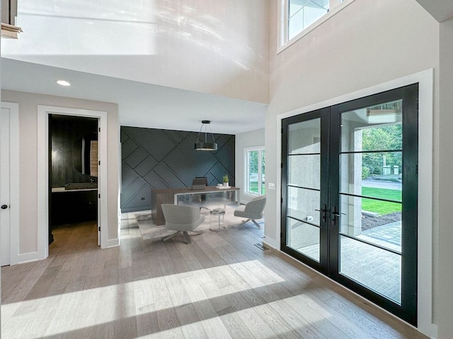 interior space with french doors, light hardwood / wood-style flooring, a healthy amount of sunlight, and vaulted ceiling