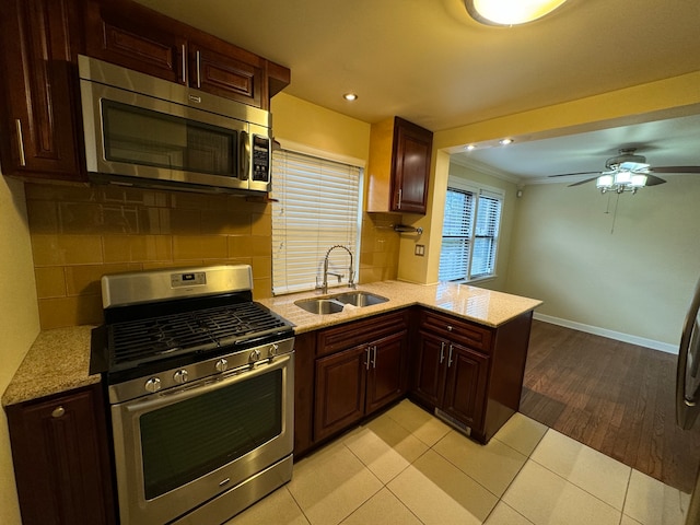 kitchen with ornamental molding, appliances with stainless steel finishes, sink, light hardwood / wood-style floors, and kitchen peninsula